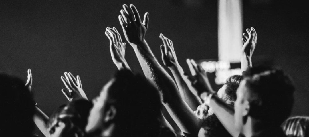 grayscale-photo-of-people-raising-their-hands-1666816